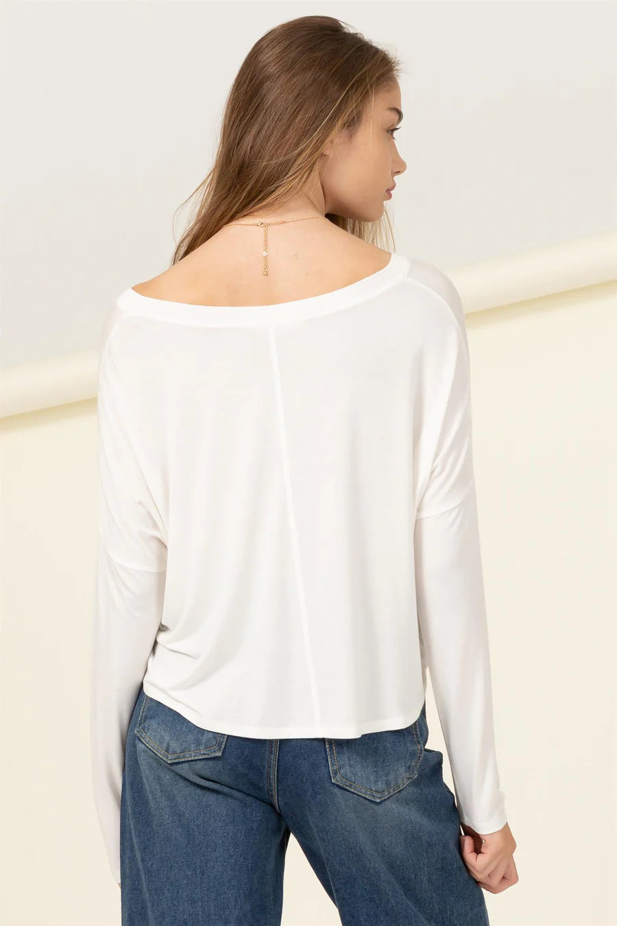 The back view of a woman wearing an Off White | Love Me Right V Neck Loose Fit Top by HYFVE.
