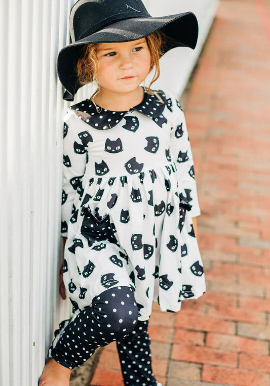 Little girl in black and white polka dot dress and hat.