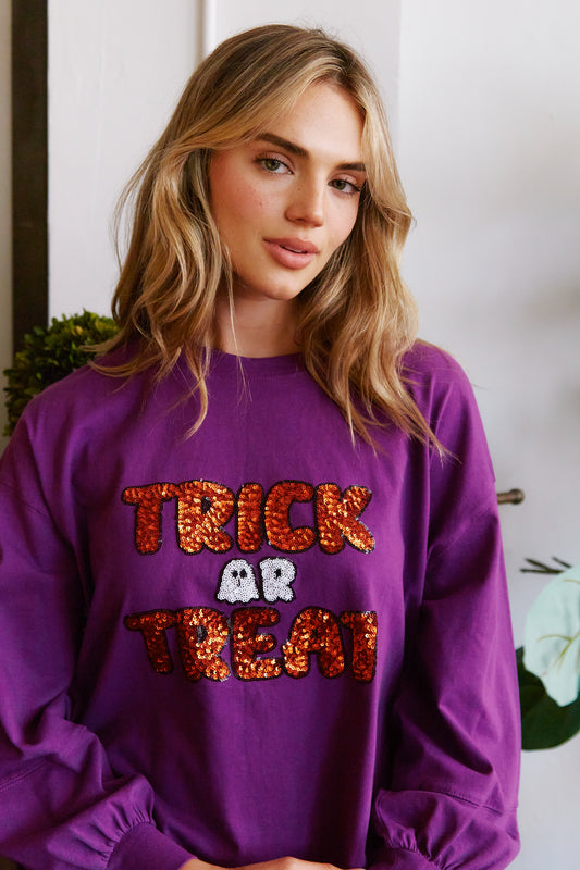 A woman donning a Fantastic Fawn Purple Trick-or-Treat sequin sweatshirt prominently displayed.
