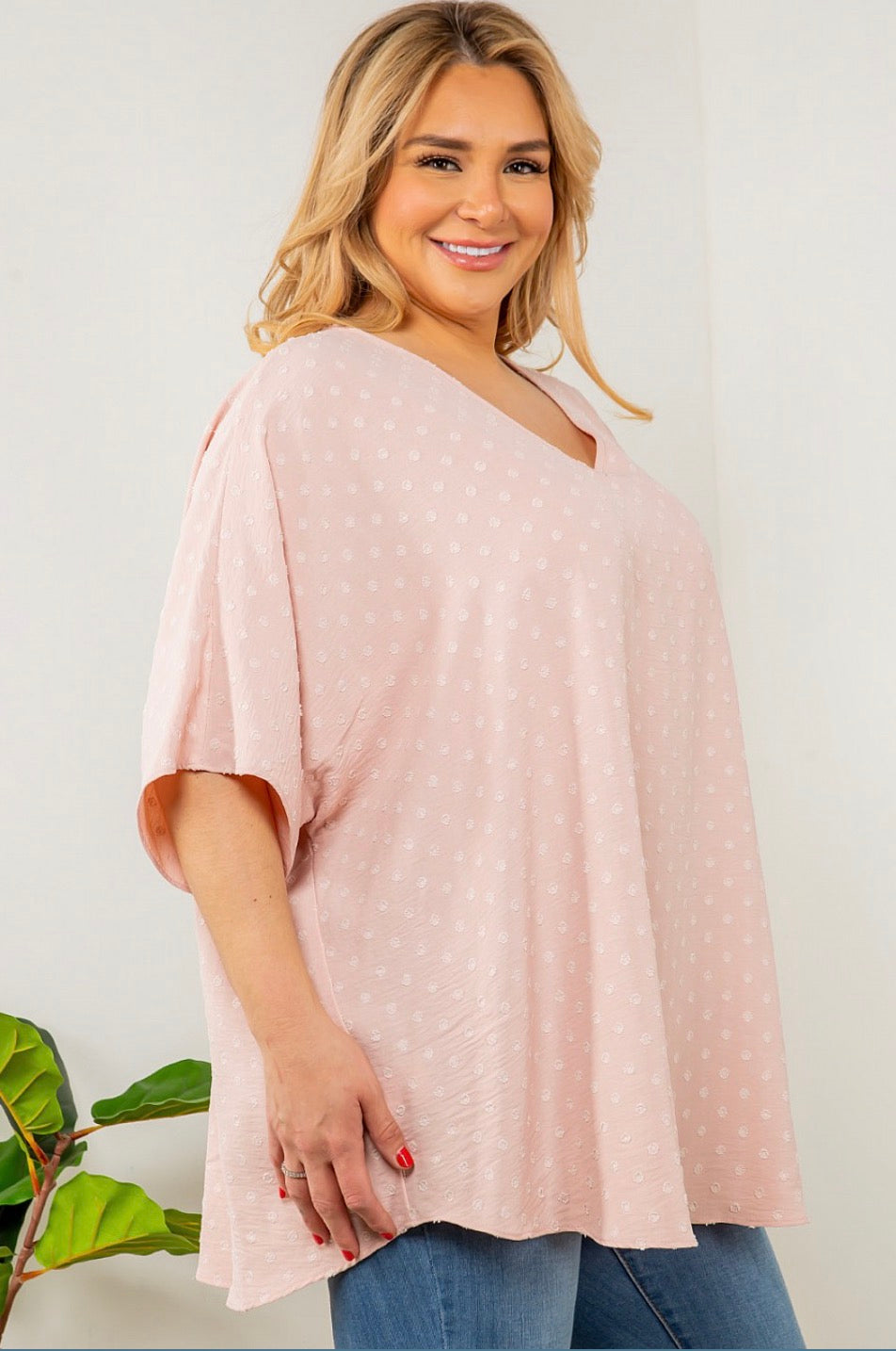 A woman wearing a Spin USA Oversized Dot V Neck Top in pink with white polka dots.