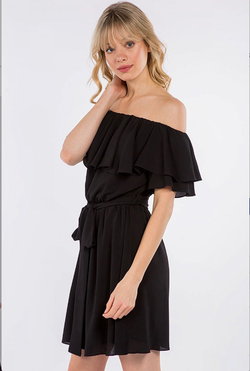 A woman in a Spin USA Off Shoulder Ruffle Dress posing for a picture.