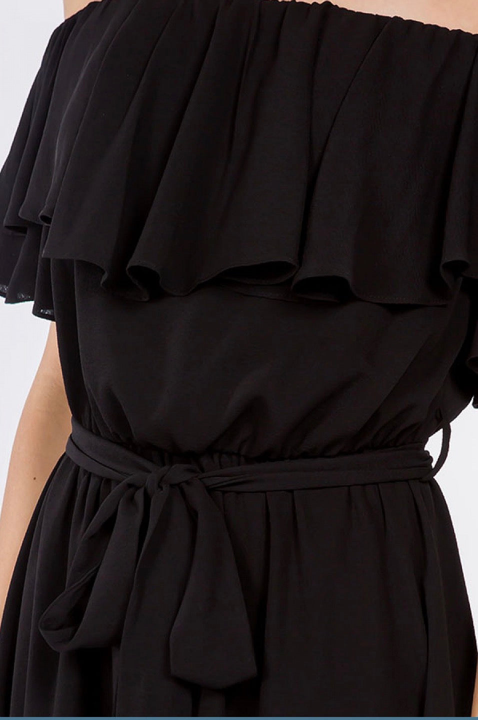 A woman wearing a black Off Shoulder Ruffle Dress with a tie around the waist from Spin USA.