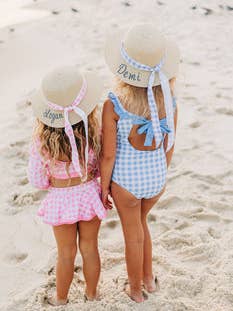 Two little girls standing in the sand at the beach wearing Sugar Bee Clothing Girls Sun Hats.