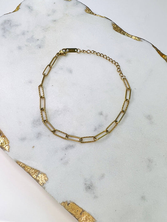An Alex Link Bracelet by Lacey Rae Jewelry on a marble table.