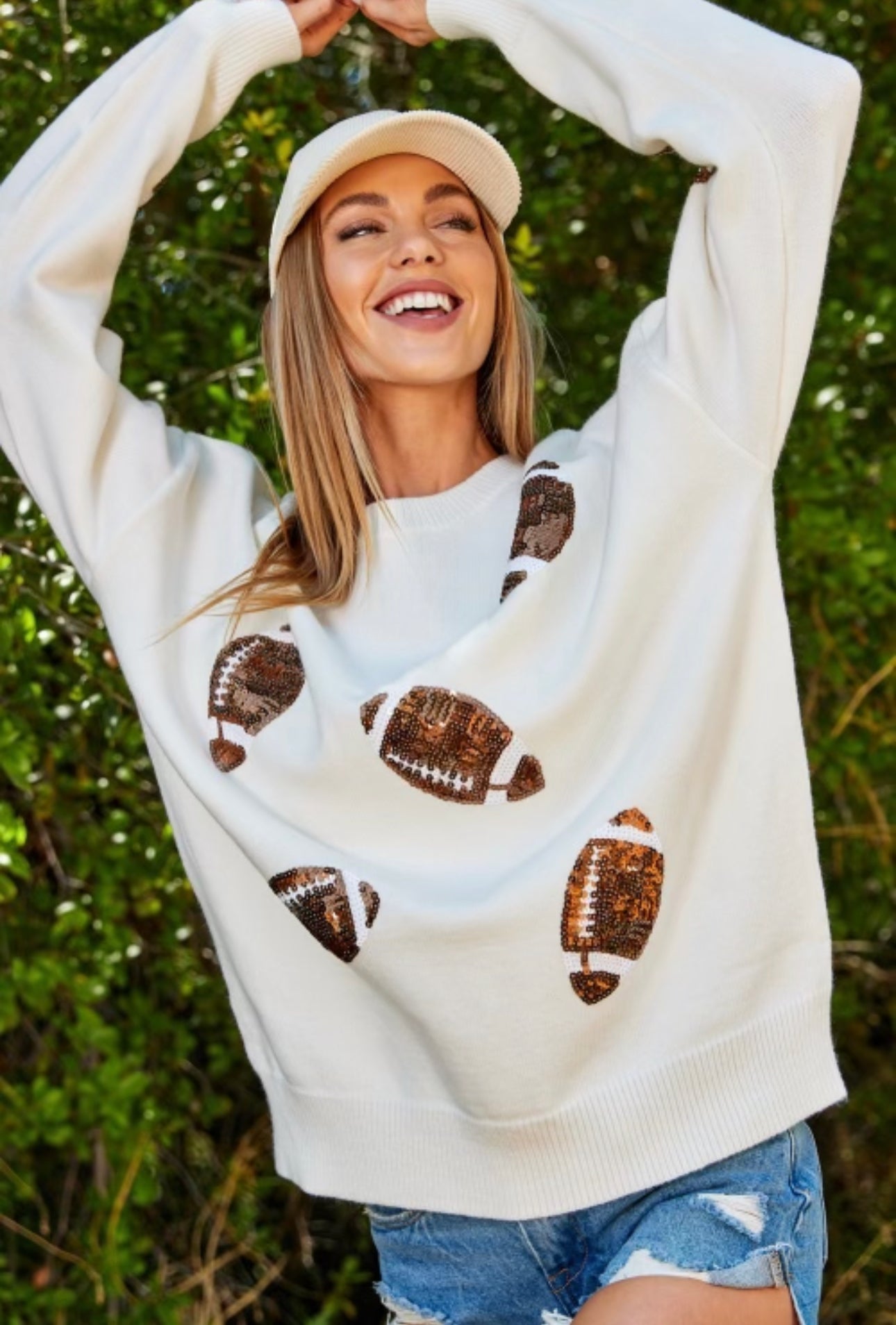 A woman wearing the Chickie Collective IVORY Game day sweater with metallic sequins patches.