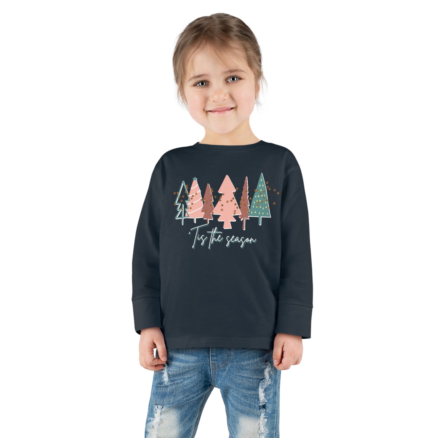 A little girl wearing a Kids Christmas Tree Long Sleeve Tee - Toddler Crew Neck T-Shirt from Printify, available in our Etsy store for kids and parents looking for a toddler long sleeve Christmas tee.