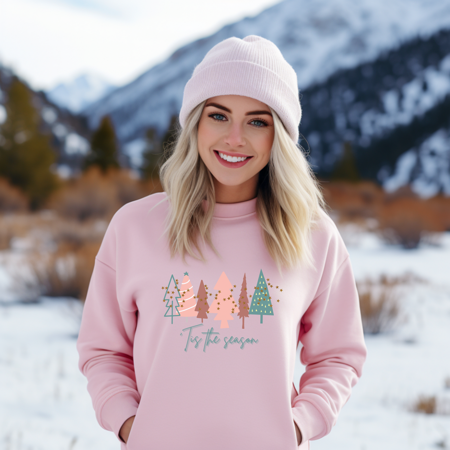 A cozy woman wearing a Printify Light Pink Christmas Tree Sweatshirt with trees on it.