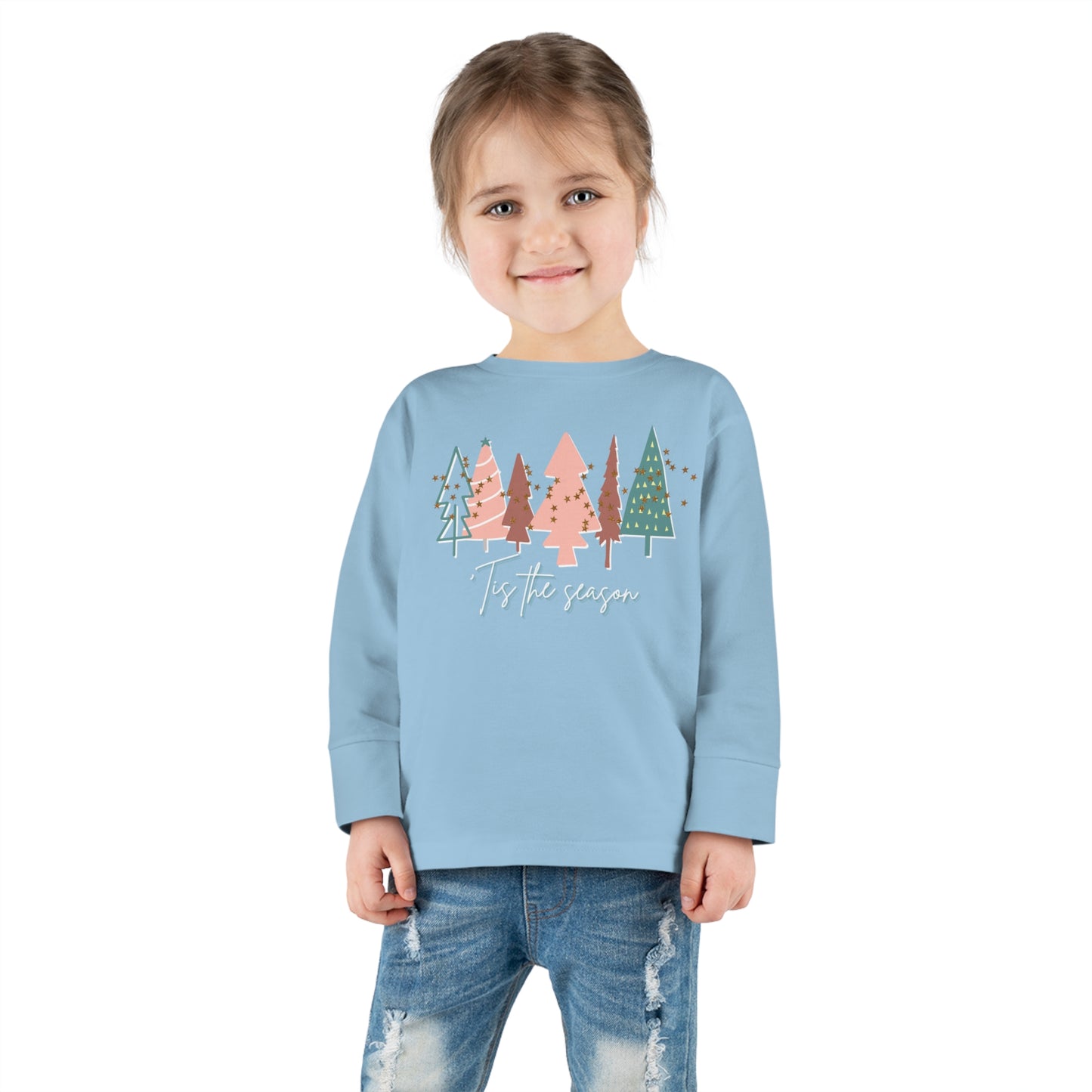 A girl wearing a blue long-sleeve t-shirt with trees on it from our Printify store, perfect for kids and parents looking for Kids Christmas Tree Long Sleeve Tee - Toddler Crew Neck T-Shirt.