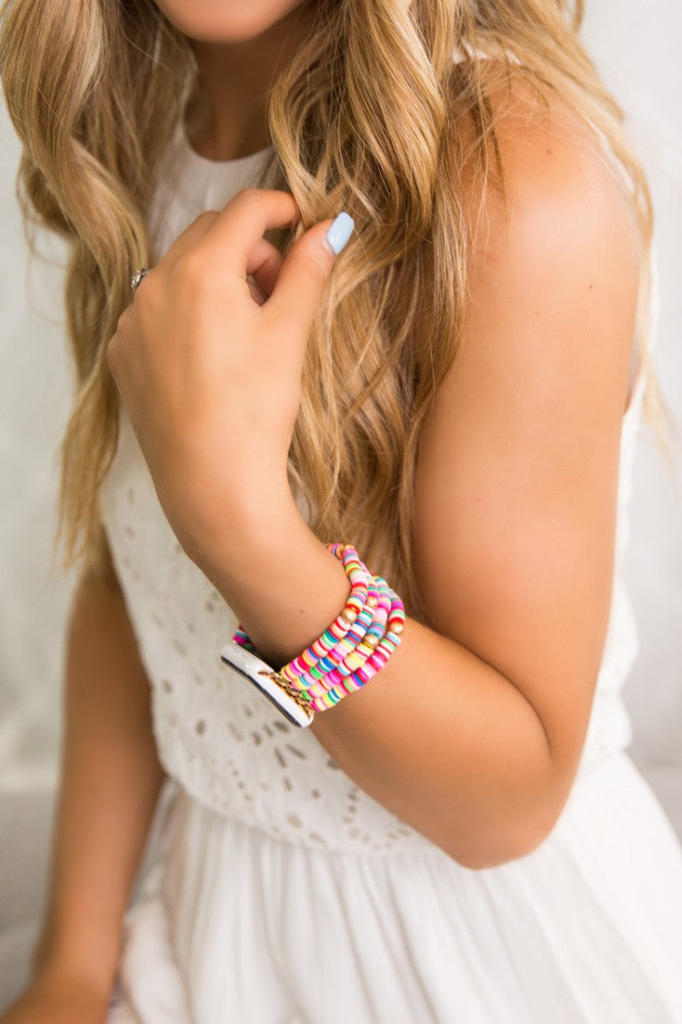A woman in a white dress is holding a Dani & Em Rainbow Silicone Watch Band.