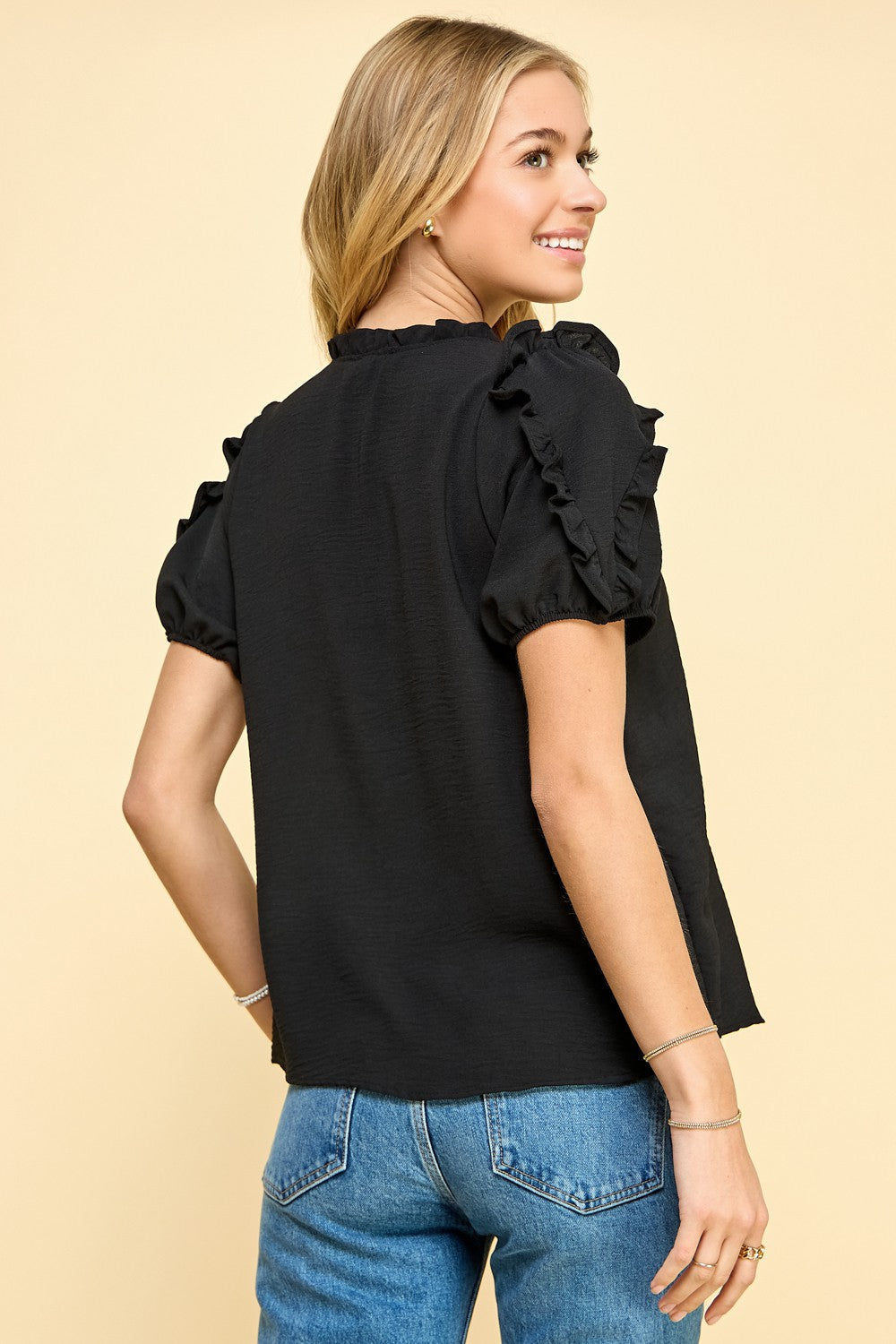 The back view of a woman wearing a Les Amis Fashion Black | Solid Ruffled Sleeves Top.
