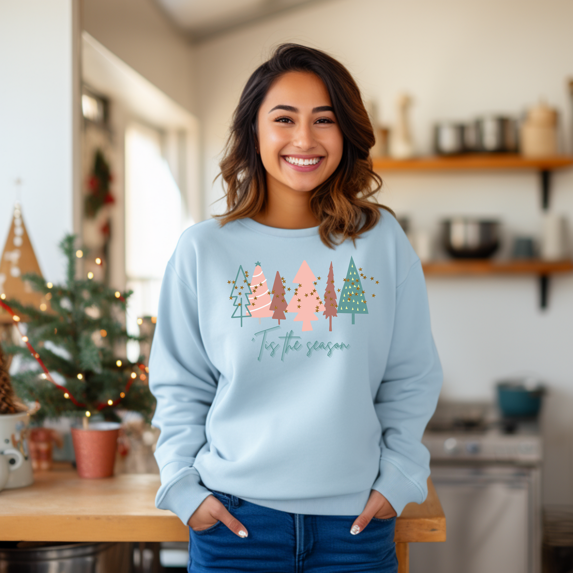 A woman wearing a cozy Printify Light Blue Christmas Tree Sweatshirt, looking warm and comfortable.