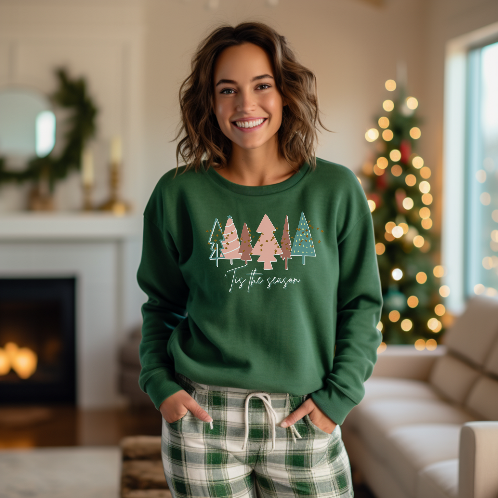 A woman wearing a Printify Forest Green Christmas Tree Sweatshirt in front of a Christmas tree.