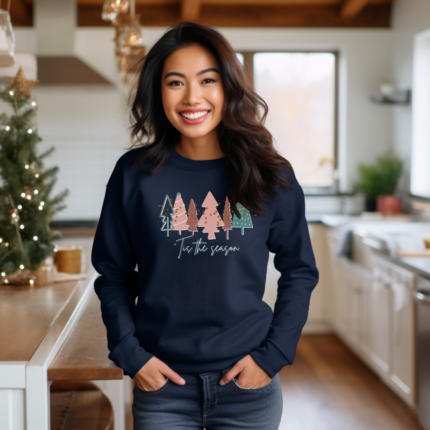 A cozy woman in a kitchen wearing a Printify Navy Christmas Tree sweatshirt.