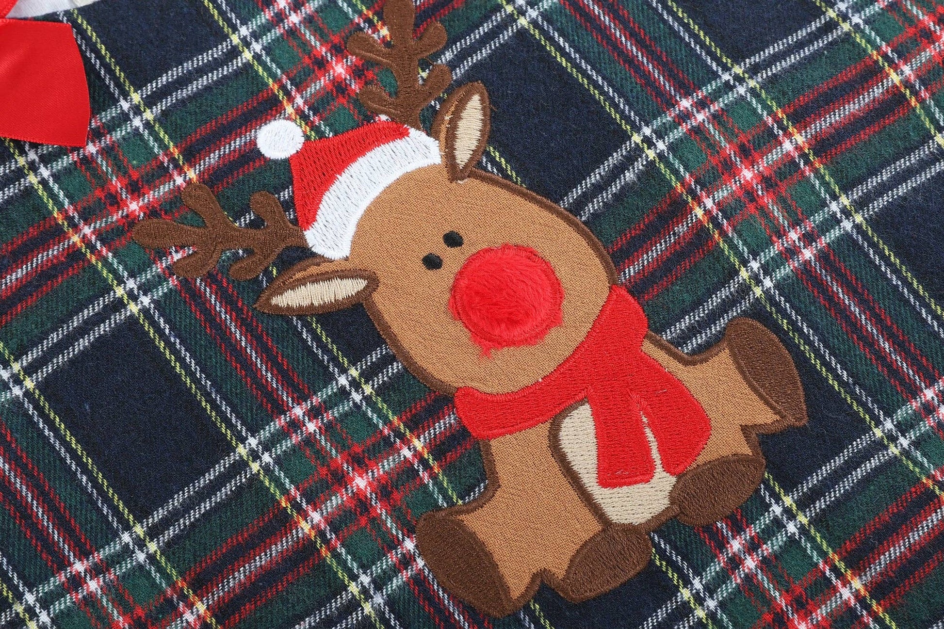 A Navy and Red Plaid Reindeer Ruffle Dress by Lil Cactus on a plaid blanket.