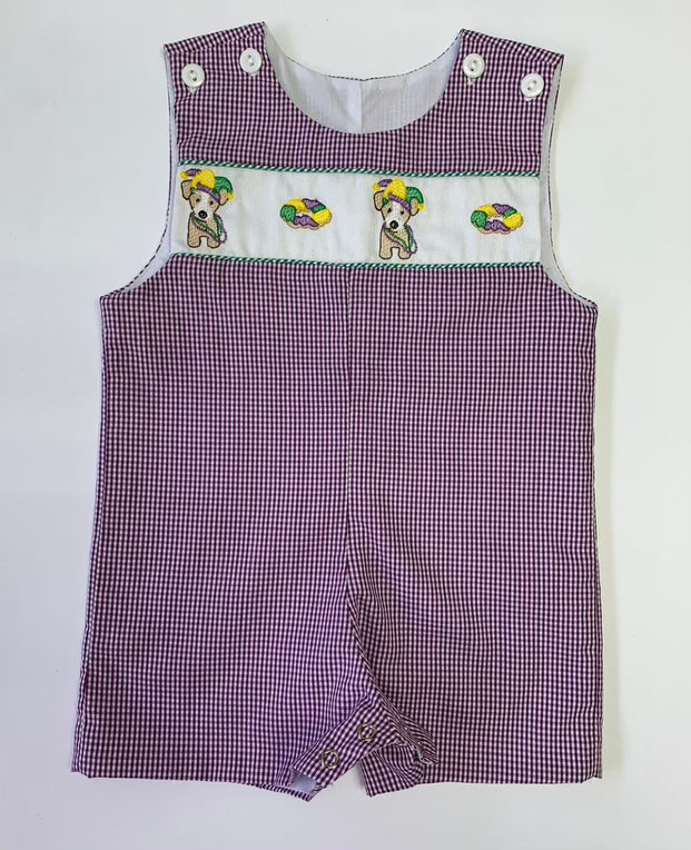 A baby boy's Mardi Gras Puppy and King Cake Shortall by Lulu Bebe, with green and white stripes, adding a festive touch to his Mardi Gras celebration.