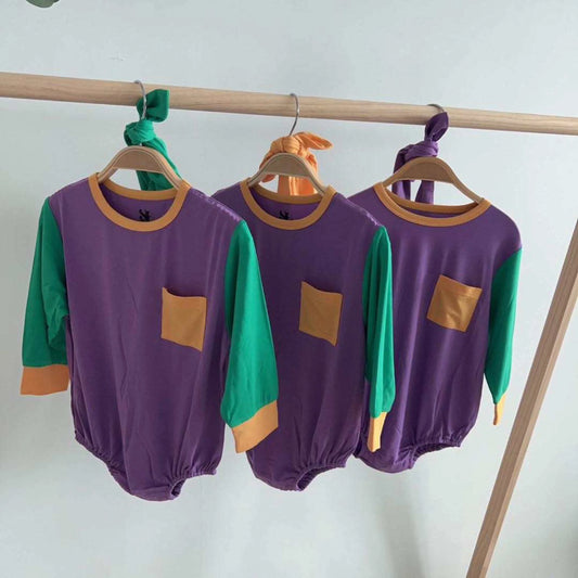 Three SeersuckerJOEY LLC Mardi Gras Color block Bamboo Baby Bubbles, in purple and green colors, are hanging on a rack.