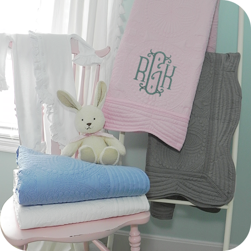 A Quilted Baby Blanket from All About Blankets sitting next to a stuffed bunny on a chair.