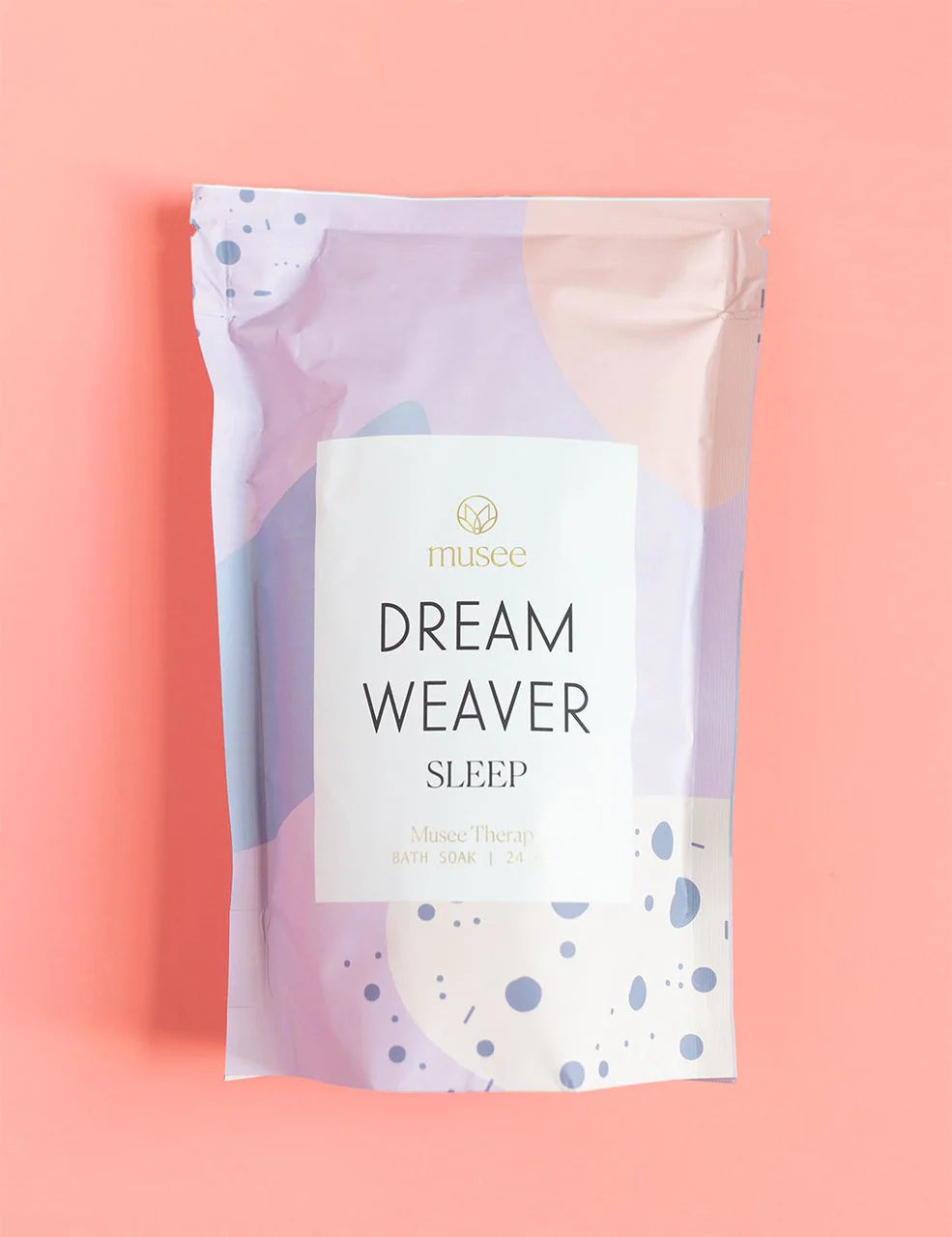 Relaxation at its finest, as Musee's Dream Weaver Bath Soak indulges in a bath soak on a pink background.