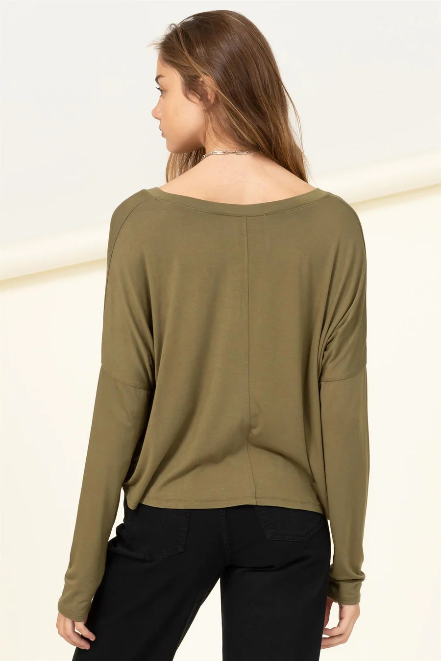 The back view of a woman wearing a HYFVE Olive Love Me Right V Neck Loose Fit Top.