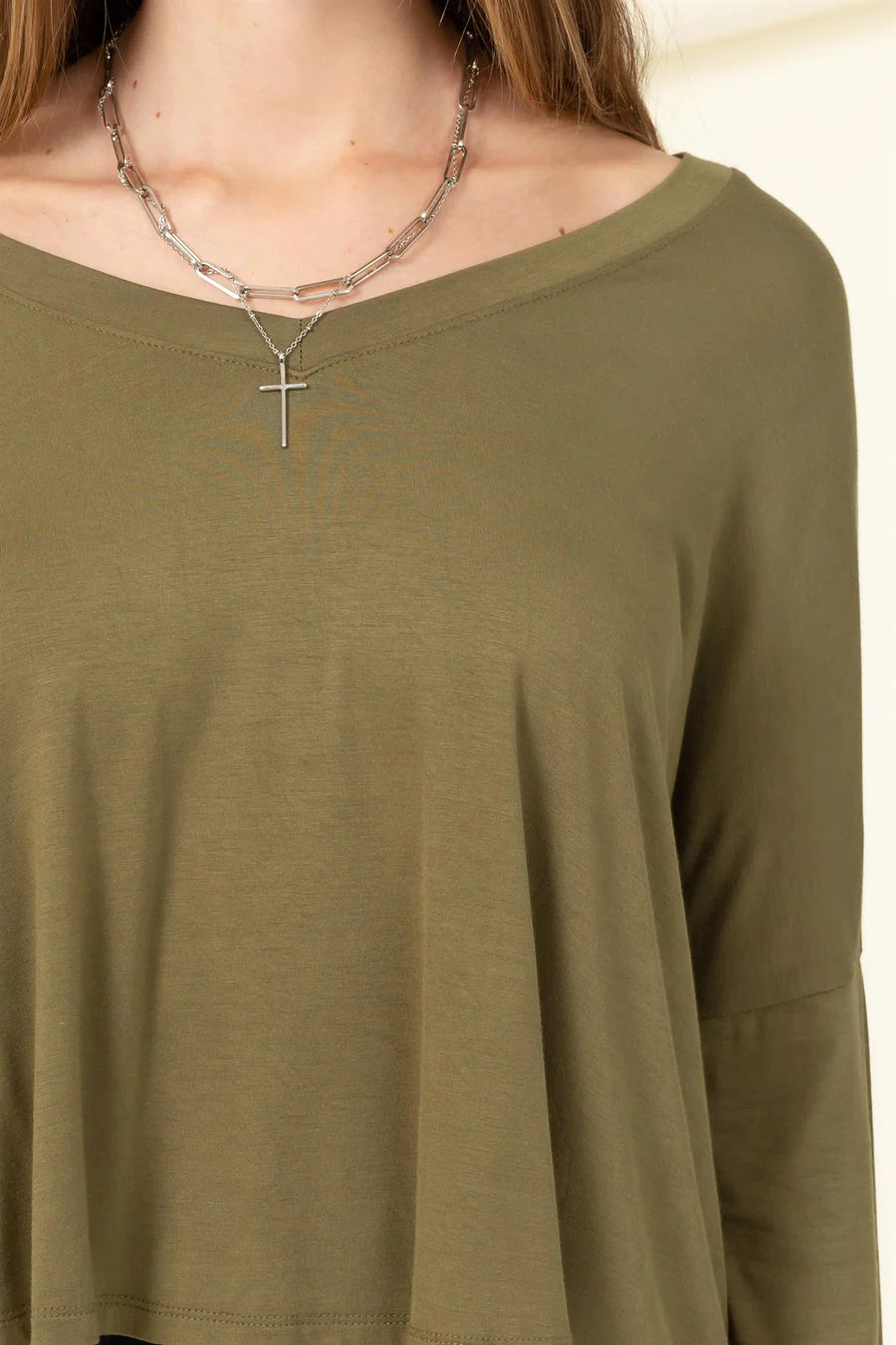 A woman wearing an Olive | Love Me Right V Neck Loose Fit Top by HYFVE with a cross necklace.