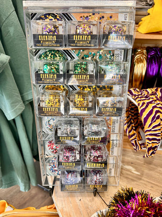 A clear display rack filled with small jars of various colored Chickie Collective Glitter Gels.