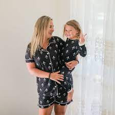 A woman and her daughter in Fleur De Lis Button Down Pajamas-Adult by Sugar Bee Clothing standing in front of a window.