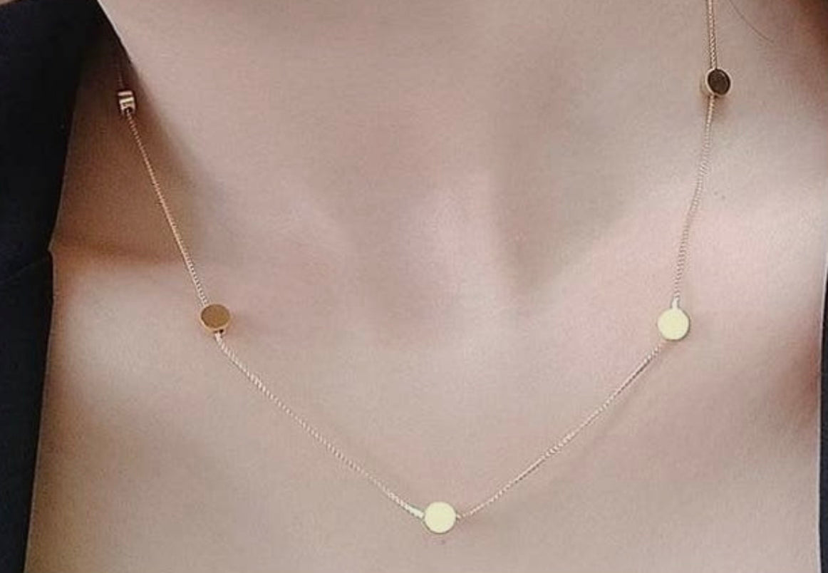 A woman is wearing a Dotti Gold Necklace from 3Souls Company with two circles on it.
