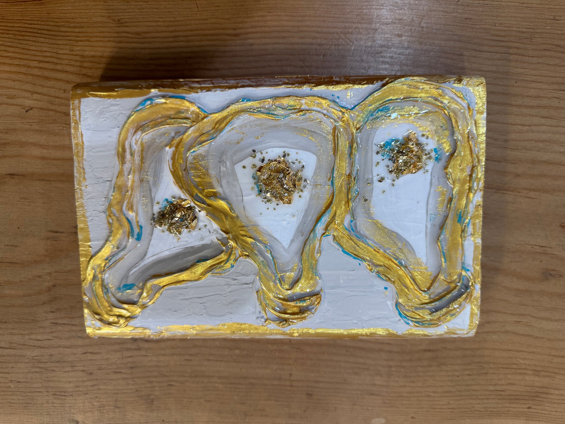 A piece of paper with three Belle & Co. gold and white Oyster Paintings on it.