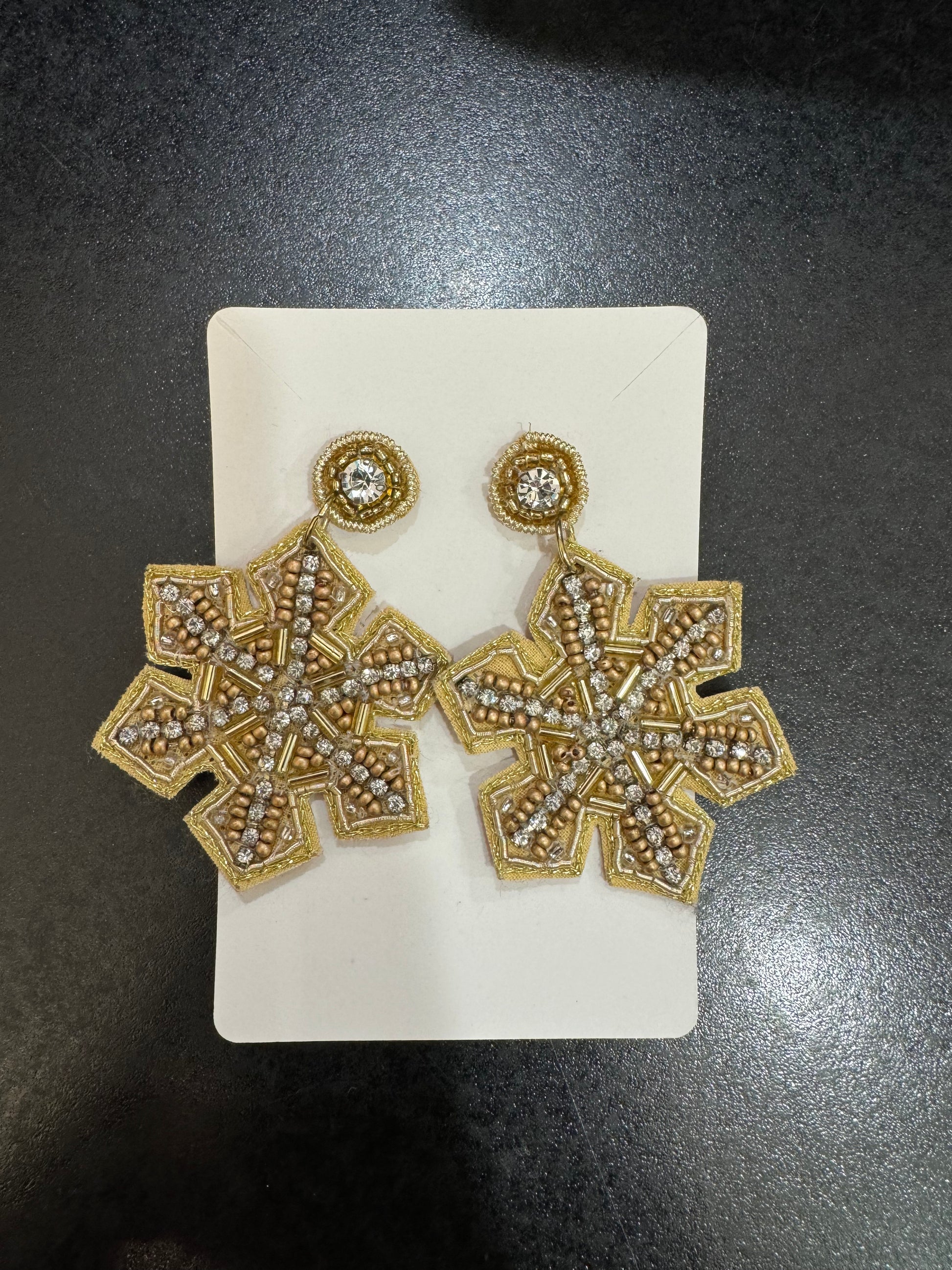 A pair of Gold Beaded Snowflake Earrings by Chickie Collective on a white background.