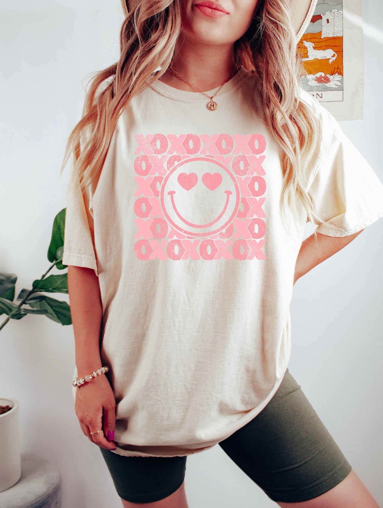 A woman wearing a pink XOXO Heart Eyes smiley valentines Graphic Tee by Chickie Collective.