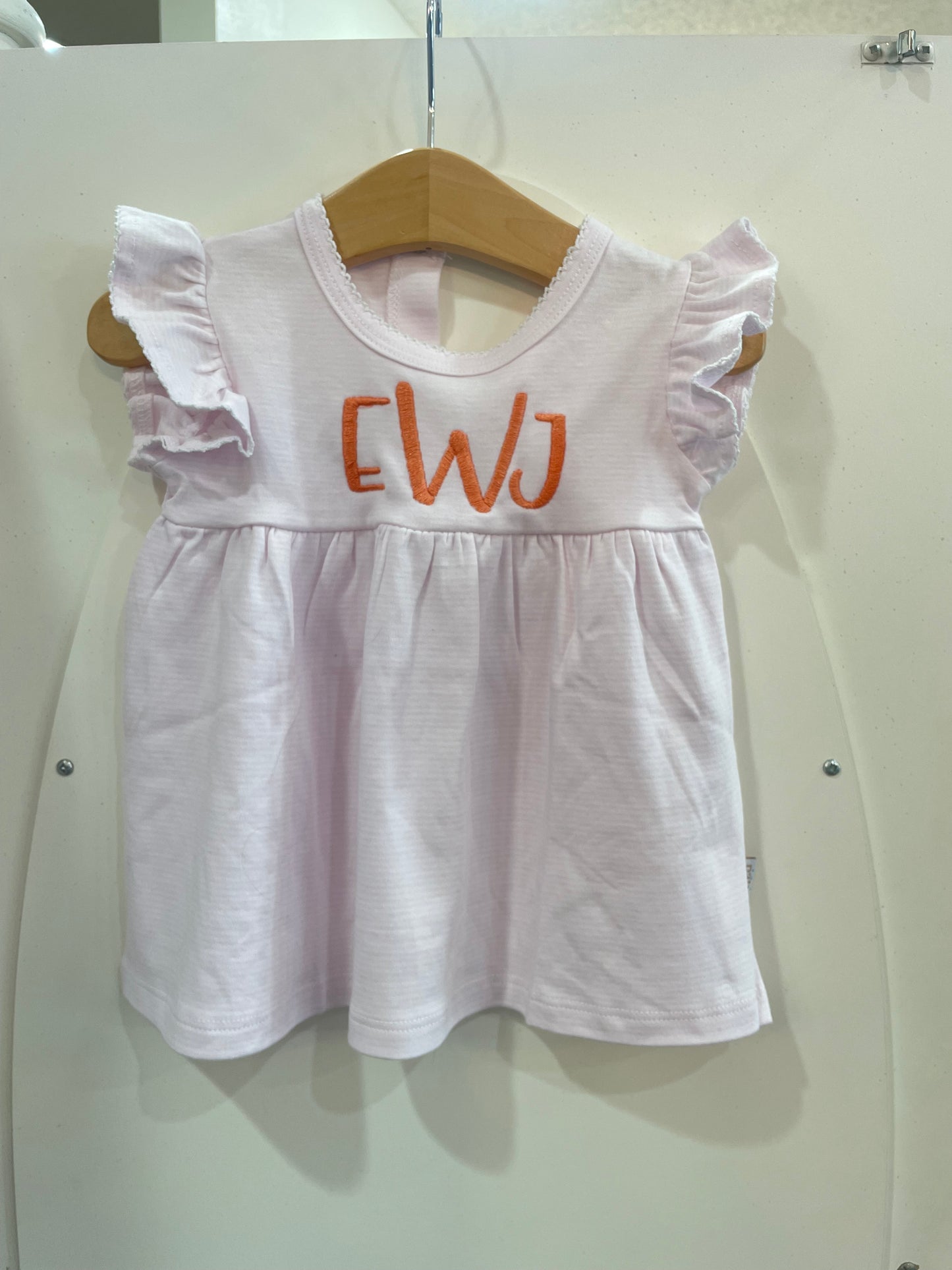 A Paty Ruffle Cotton Dress with orange letters on it.