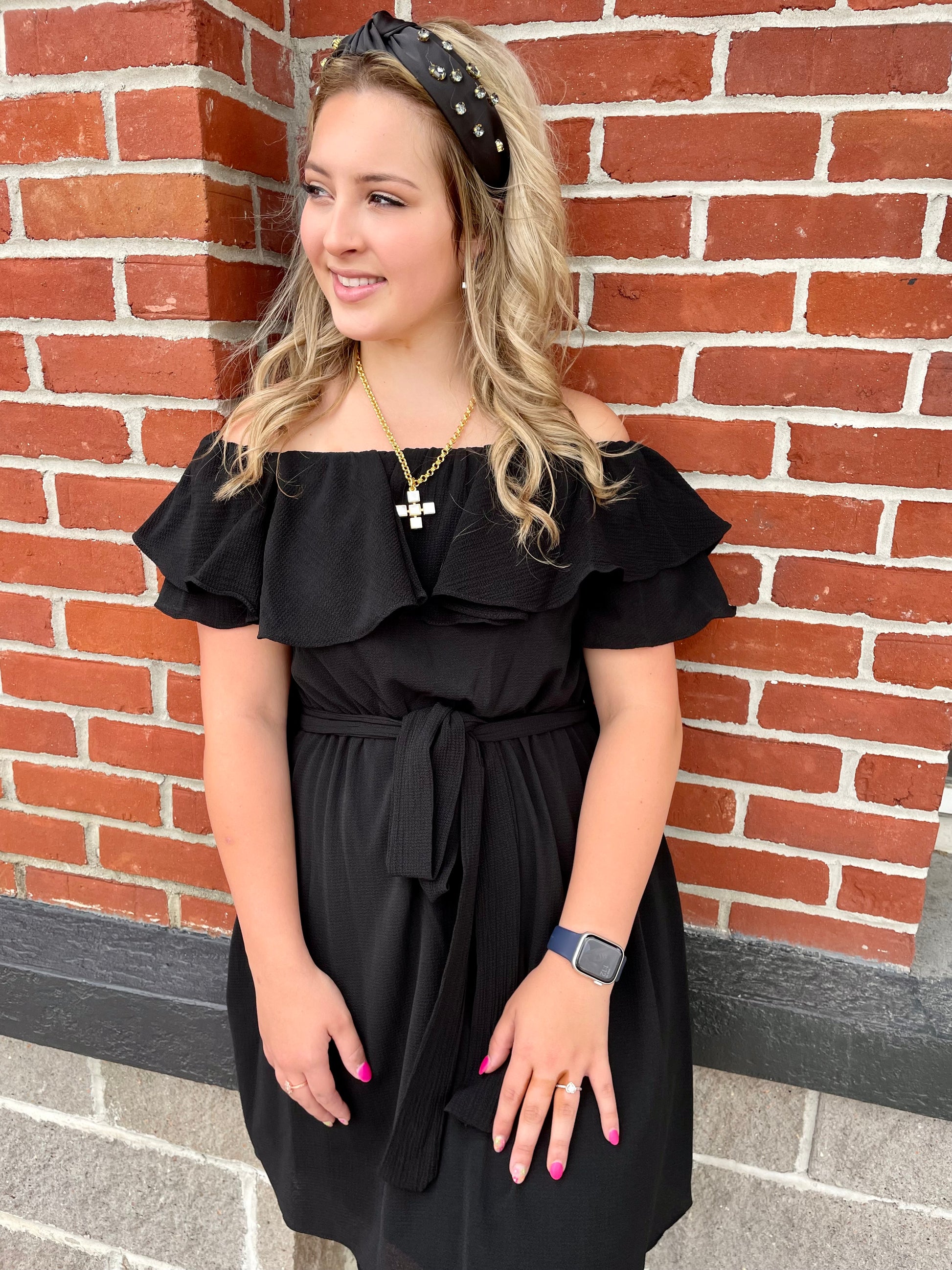 a girl in a black dress standing in front of a brick wall wearing MOP Cross Earrings by Weisinger Designs.