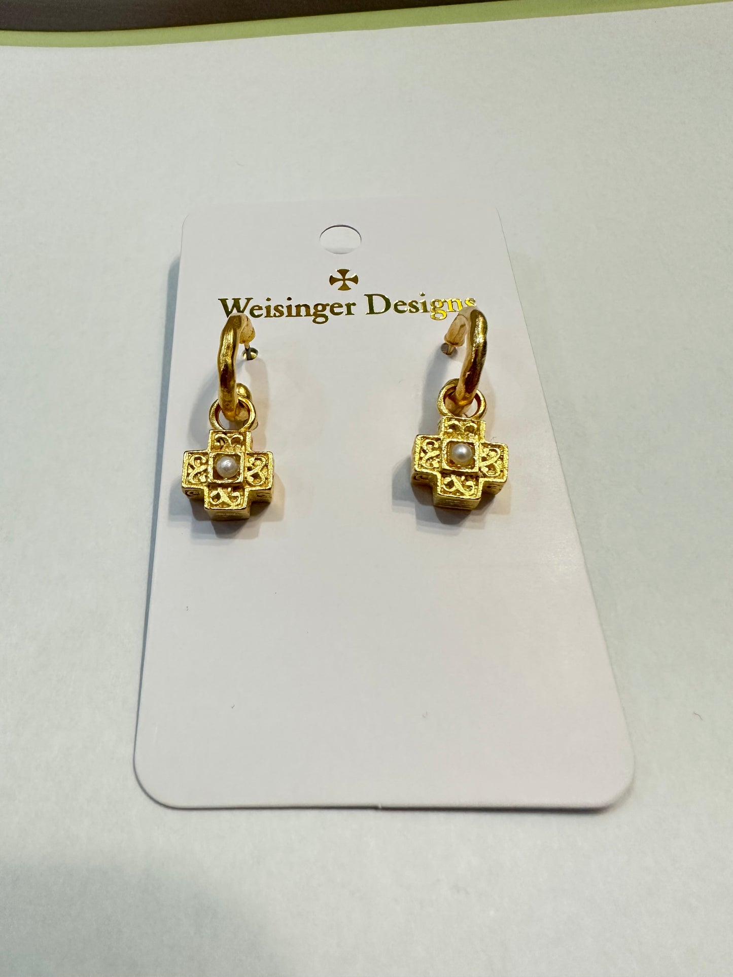 A pair of high-quality Weisinger Designs gold-plated earrings featuring a Filigree Cross with Pearl Center on Hoop Stud design on a card.
