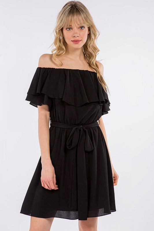 A woman is wearing a black Off Shoulder Ruffle Dress from Spin USA with a bow.
