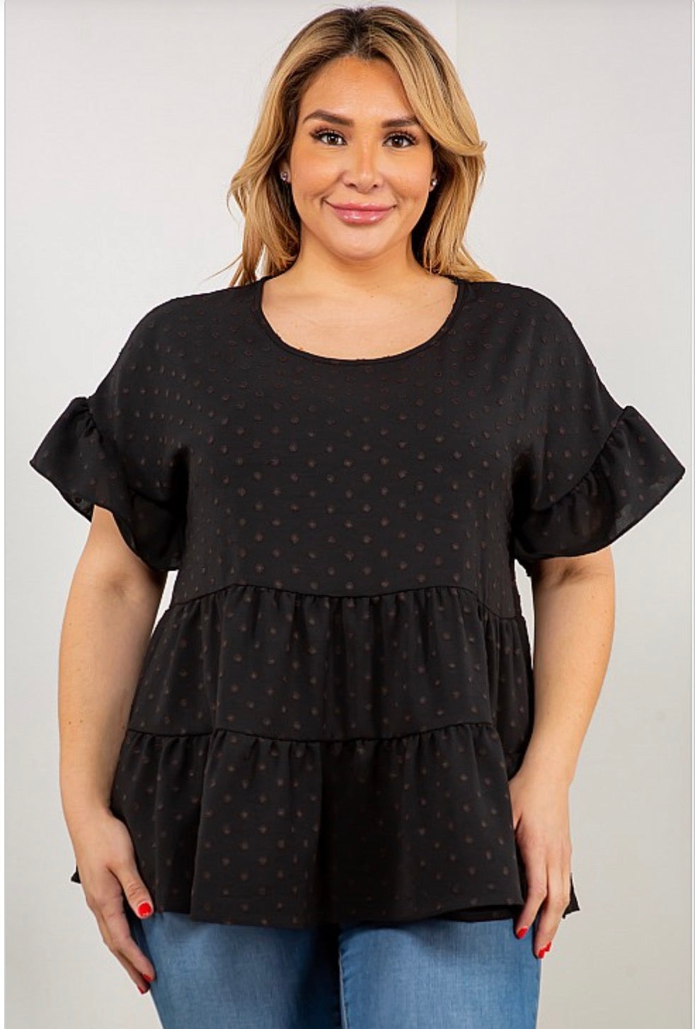 A woman wearing a Dot Ruffle Sleeve, Multi Tier Tunic Top from Spin USA in black with polka dots.