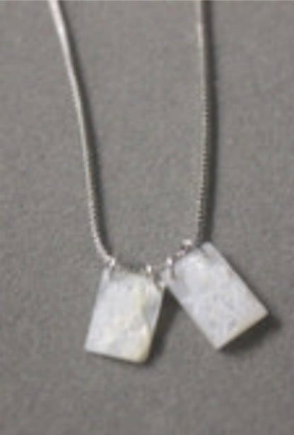 A Weisinger Designs silver necklace adorned with two small squares, serving as a meaningful accessory.