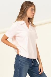 The model is wearing a pink HYFVE Blush | Out & About Collared Short-Sleeve Top and jeans.
