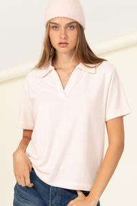 The model is wearing a blush HYFVE polo shirt and jeans.