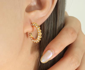 A woman's ear adorned with a WS-Star Dust gold hoop earring by 3Souls Company.