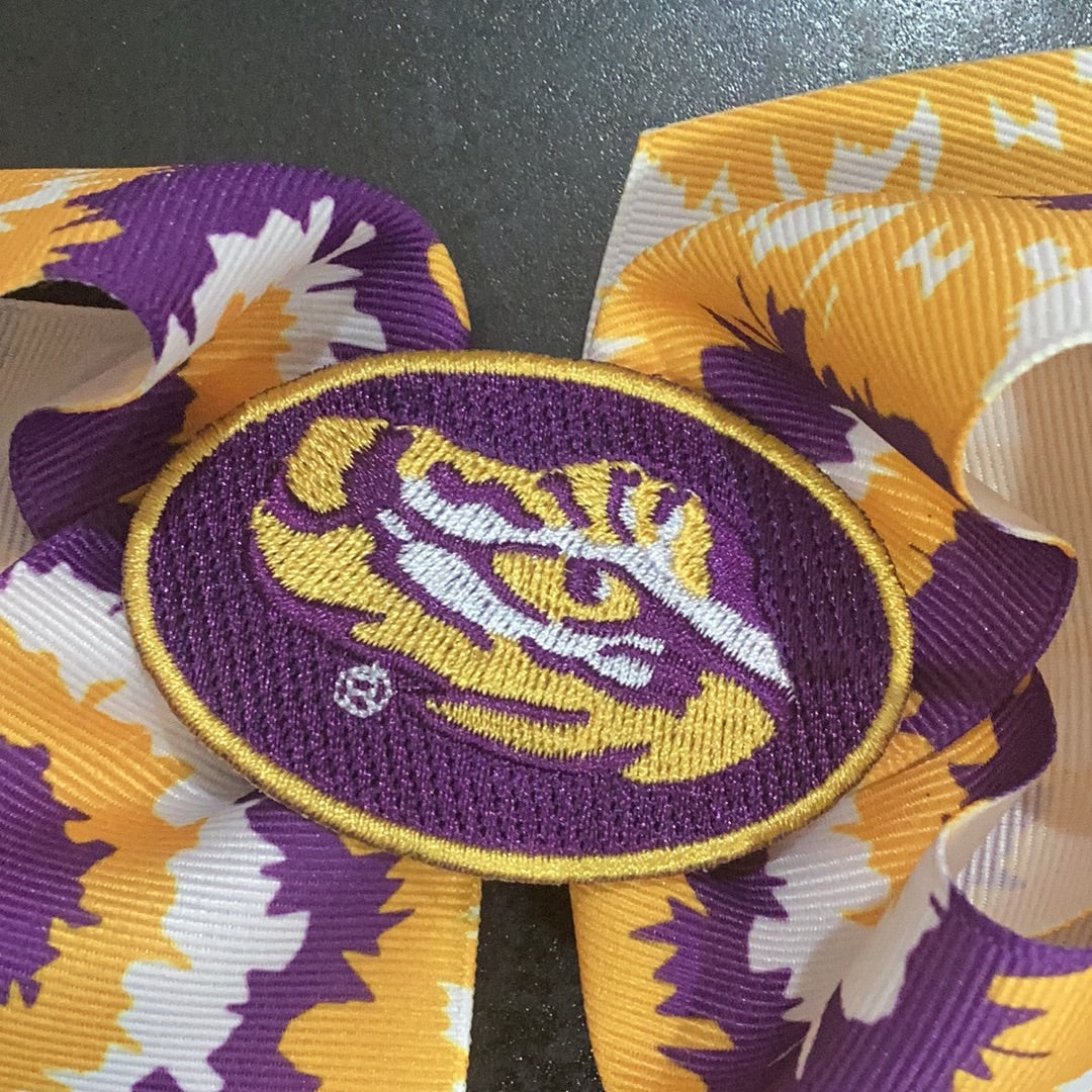 A Wee Ones LSU Tie-Dye Bow with the embroidered Eye of the Tiger design.