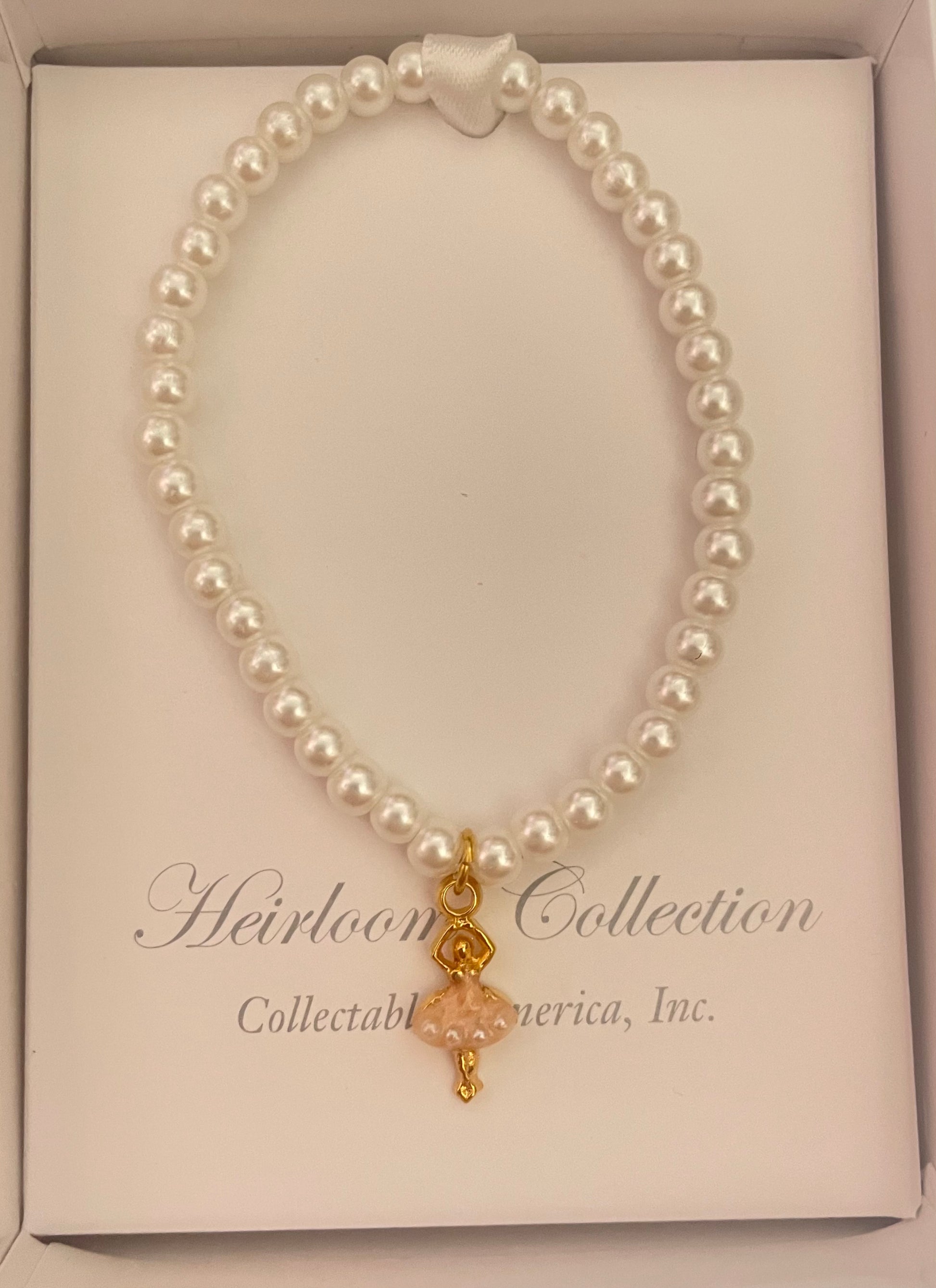 A Collectables America Pearl Ballerina Bracelet with a gold cross charm.