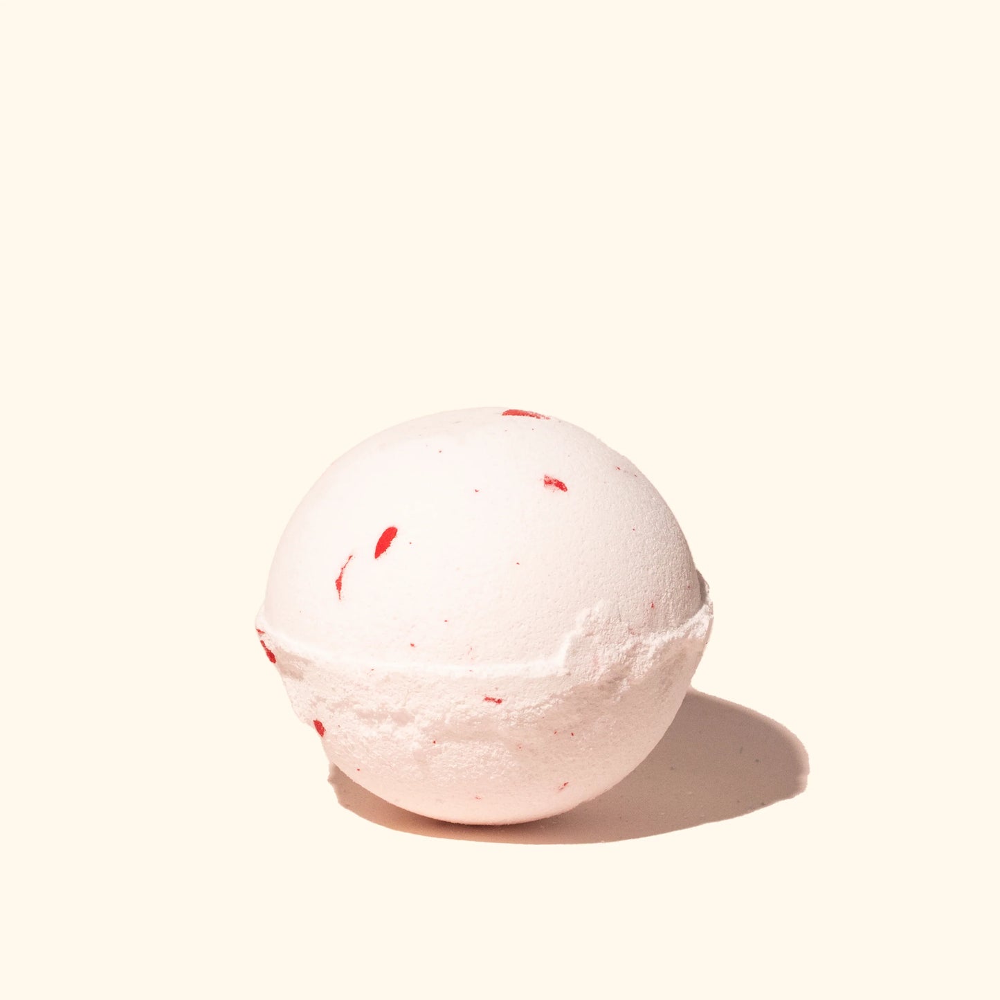 A pink and white Musee Jingle Bells Surprise Bath Balm with a surprise inside.