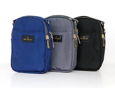 Three different colors of DM Merchandising's Kedzie Crosstown Crossbody Bag Assortment sitting next to each other.