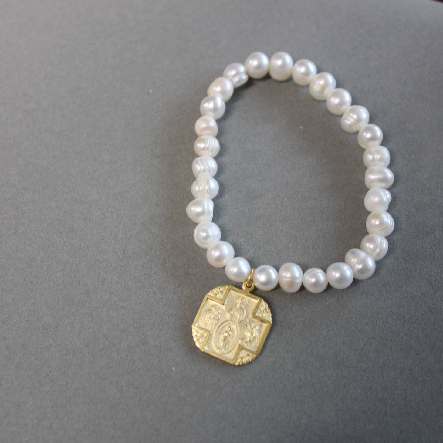 A Pearl Stretch Bracelet with Square 4 Way Cross Medal from Weisinger Designs.