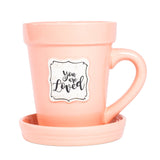 A Peach Flower Pot Mug - You Are Loved by Nicole Brayden with a saucer and saucer on it.