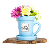 A "Blue Flower Pot Mug - Best Friend" by Nicole Brayden sitting on a piece of wood.