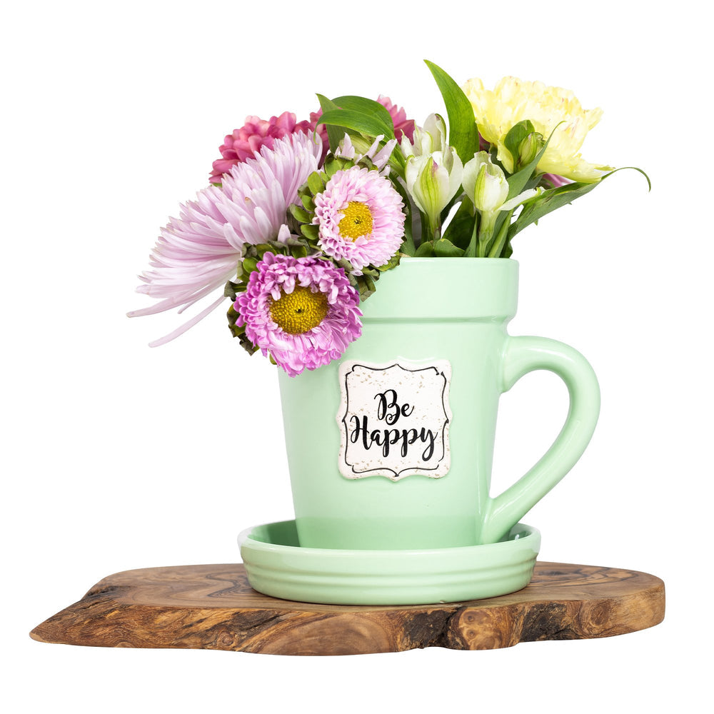 A Green Flower Pot Mug - Be Happy by Nicole Brayden with a bouquet of flowers in it.