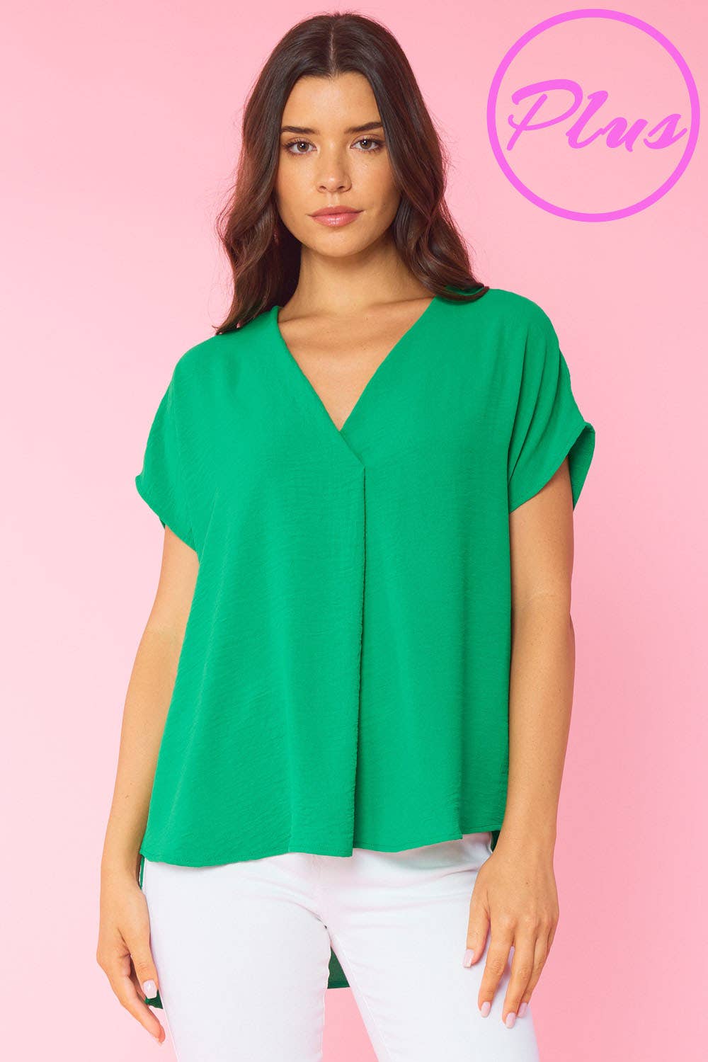 A woman wearing a KELLY GREEN - SOLID V NECK RELAXED FIT SHORT SLEEVE TOP by FSL Apparel and white jeans.