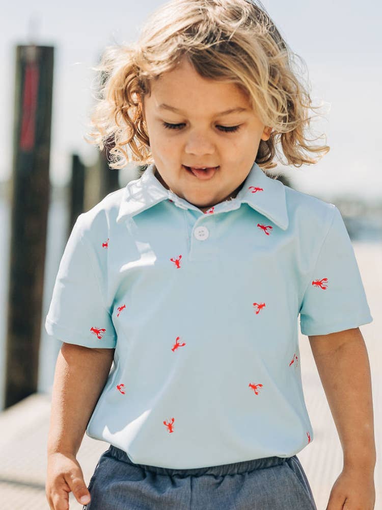 A little girl standing on a dock with her hands in her pockets wearing a Crawfish Polo Shirt by Sugar Bee Clothing.