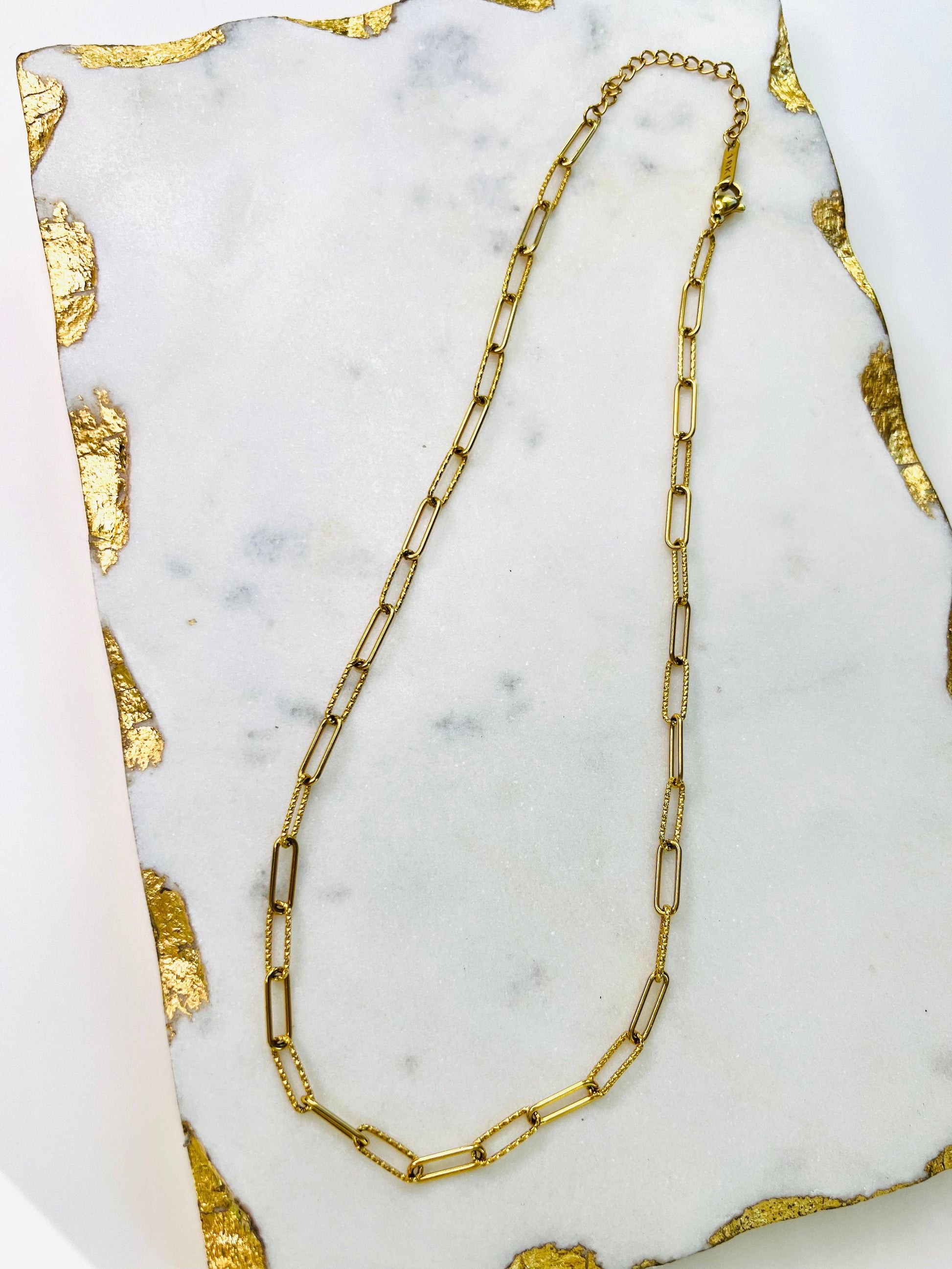 An Alex Link Necklace by Lacey Rae Jewelry on a marble surface.